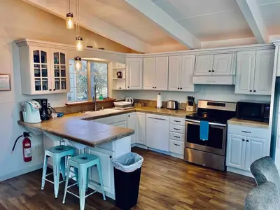 a kitchen with white cabinets and a wooden floor at Black Bear Suite Hot Tub Sleeps 4 affordable in Oakhurst