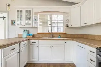 a white kitchen with white cabinets and a sink at Black Bear Haven Hot tub Pool table BBQ Darts in Oakhurst