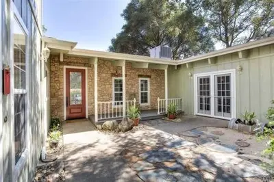 a brick house with a red door and a yard at Black Bear Haven Hot tub Pool table BBQ Darts in Oakhurst