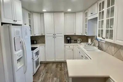 a white kitchen with white appliances and wooden floors at Deer Suite HOT TUB GAME ROOM SLEEPS 2 in Ahwahnee