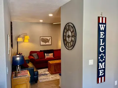 a living room with a red couch and a clock on a wall at Eagle Nest River Views Hot Tub Games Sleeps 6 in Ahwahnee