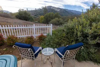two chairs and a table on a patio with a fence at The Funky Chicken Hot Tub BBQ SLEEPS 4 in Ahwahnee