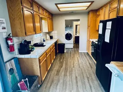a kitchen with wooden cabinets and a black refrigerator at Lighthouse Suite Pet Friendly Hot Tub Sleeps 4 in Coarsegold