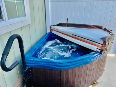 a hot tub in a bucket next to a house at Raccoon Hideout Hot Tub BBQ Arcade Darts in Oakhurst