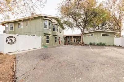 a green house with a white fence in a driveway at Raccoon Hideout Hot Tub BBQ Arcade Darts in Oakhurst