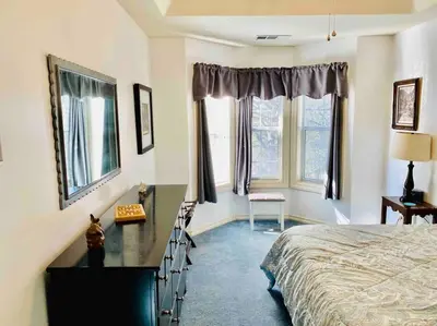 a bedroom with a bed and a desk and windows at Squirrel View Hot tub BBQ Patio Shuffle Board in Oakhurst