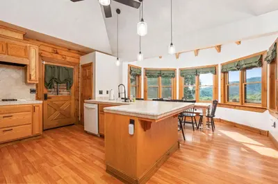 a kitchen with a large island in a kitchen with wooden floors at Yosemite Villa - log cabin with spectacular views & stargazing in Mariposa