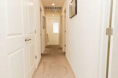 a hallway with white walls and a white door at Modern 5 bed near hospitals and UC Merced in Merced