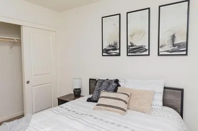 a bedroom with a white bed with four pictures on the wall at Modern 5 bed near hospitals and UC Merced in Merced