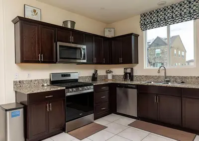 a kitchen with wooden cabinets and a stove top oven at Modern 5 bed near hospitals and UC Merced in Merced