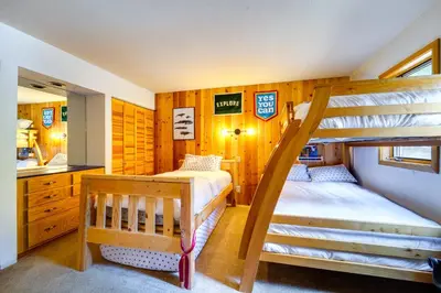 a bedroom with two bunk beds and a kitchen at 5 Mi to Donner Lake Cabin with Deck and Pool Access! in Truckee