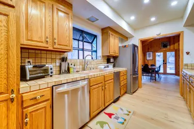 a kitchen with wooden cabinets and stainless steel appliances at 5 Mi to Donner Lake Cabin with Deck and Pool Access! in Truckee