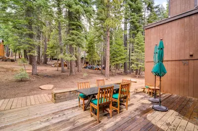 a patio with a table and chairs and an umbrella at 5 Mi to Donner Lake Cabin with Deck and Pool Access! in Truckee