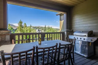 a table and chairs on a deck with a grill at Creekhouse 1583 in Mammoth Lakes