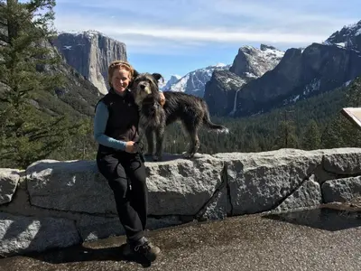 a woman standing on a stone wall with a dog at Morning Star Vista near Yosemite - countryside with mountain views in Mariposa