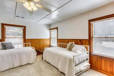 two beds in a room with wooden walls and windows at Spacious Coarsegold Getaway about 34 Mi to Yosemite! in Coarsegold