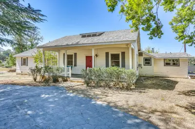 a white house with a red door and a driveway at Spacious Coarsegold Getaway about 34 Mi to Yosemite! in Coarsegold