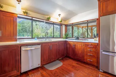 a kitchen with wooden cabinets and a large window at Sequoia River House, close to SNP, 2 Decks on Amazing River on 7acres in Three Rivers