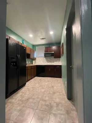 a kitchen with a black refrigerator and wooden cabinets at Fresno Vacation Rental 106 in Fresno