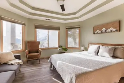 a bedroom with a bed and a chair and windows at Number 1! PARADISE Getaway - Sequoia Alta Vista in Three Rivers
