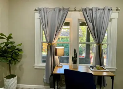 a table with a lamp and a window with curtains at Artists Bungalow ARCADE King Beds near the beat in Sacramento