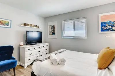a bedroom with a bed and a tv and a blue chair at Smart Eclectic ART HOUSE near UC Davis Med Center in Sacramento