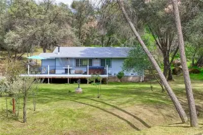 a blue house in the middle of a yard at Brookside Cottage in Mariposa