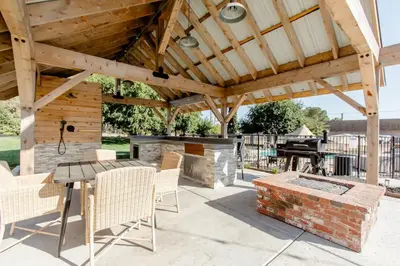 an outdoor patio with a fireplace and a wooden pergola at Beautiful spacious guest home in Roseville
