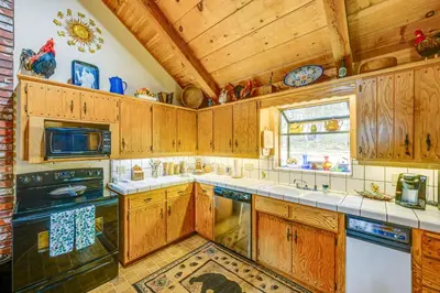 a kitchen with wooden cabinets and a stove top oven at Countryside Views Family-Friendly Badger Cabin in Badger