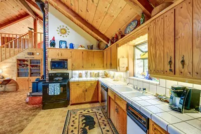 a large kitchen with wooden cabinets and a staircase at Countryside Views Family-Friendly Badger Cabin in Badger