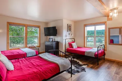 three beds in a room with windows and red sheets at The Modern Moose Lodge in Truckee