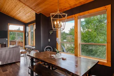 a dining room with a wooden table and windows at The Modern Moose Lodge in Truckee