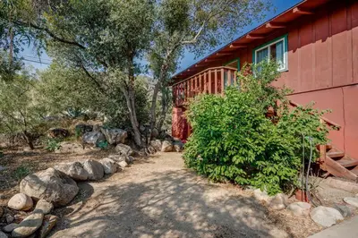 a red house with a path next to a building at Scenic Kernville Getaway with Deck and Mountain Views! in Kernville