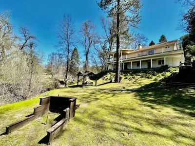 a large house sitting on top of a grass field at Creekside Suite Sleeps 2 Creek frontage Bbq in Oakhurst