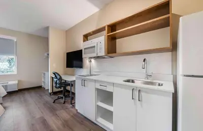 a kitchen with white cabinets and a sink and a desk at Extended Stay America Premier Suites - Reno - Sparks in Sparks