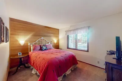 a bedroom with a bed with a red bedspread and a window at Meadow Ridge 34 in Mammoth Lakes