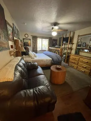 a living room with two beds and a leather couch at Stewart Chalet @ Yosemite/Bass Lake in Bass Lake