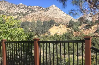 a black fence with a mountain in the background at Tillie Creek Retreat: a Creekside Oasis in Wofford Heights