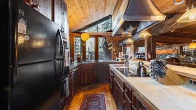 a kitchen with wooden cabinets and a black refrigerator at Mt. Jola by AvantStay A 5-minute walk away to Palisades and lifts. in Olympic Valley