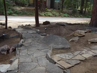 a stone walkway in a yard with rocks and trees at The Knotty Cabin in Kings Canyon National Park in Wilsonia