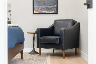a black arm chair sitting next to a bed at The Moro | Sequoia Motel RM3 in Three Rivers