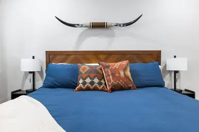 a bed with blue sheets and pillows with horns on the wall at The Rae | Sequoia Motel RM 5 in Three Rivers