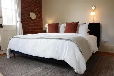 a large white bed in a room with a brick wall at Imperial Hotel + Restaurant in Amador City