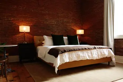 a bedroom with a bed and a brick wall at Imperial Hotel + Restaurant in Amador City
