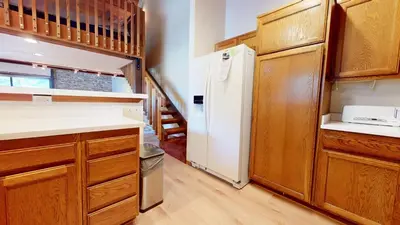 a kitchen with a white refrigerator and wooden cabinets at Snowcreek I #52 condo in Mammoth Lakes