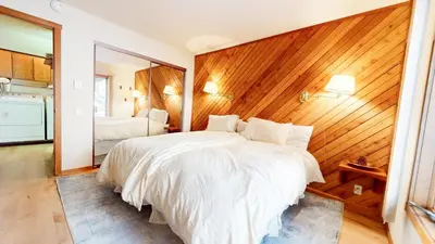 a bedroom with a white bed and a wooden wall at Snowcreek I #52 condo in Mammoth Lakes