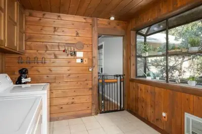 a kitchen with a wooden wall with a door and a window at Cedar Ridge Hot Tub BBQ Sleeps 8 in Oakhurst