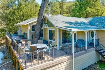 a house with a deck with a table and chairs at Cedar Ridge Hot Tub BBQ Sleeps 8 in Oakhurst