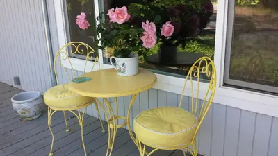 a yellow table and two chairs on a porch with flowers at Yosemite Plaisance Bed & Breakfast in Mariposa