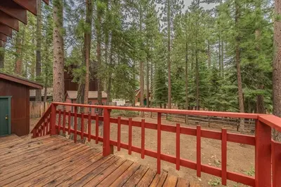 a red railing on a wooden deck in the woods at Cozy Pet-Friendly Cabin w Fenced-In Yard Close to Slopes Beach Town in Carnelian Bay